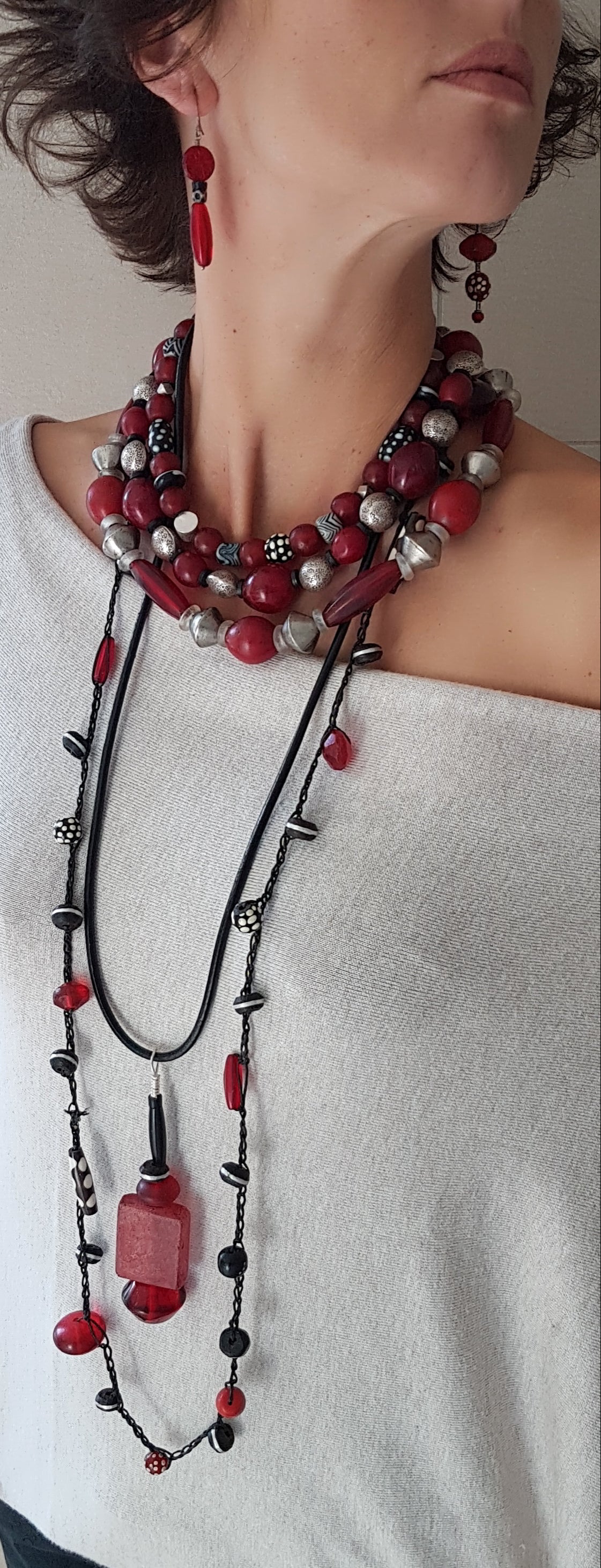 Lange handgehäkelte Kette, ein Mix aus Glas, Harz, Ebenholz und Bein in Rot- und Schwarztönen auf Baumwolle