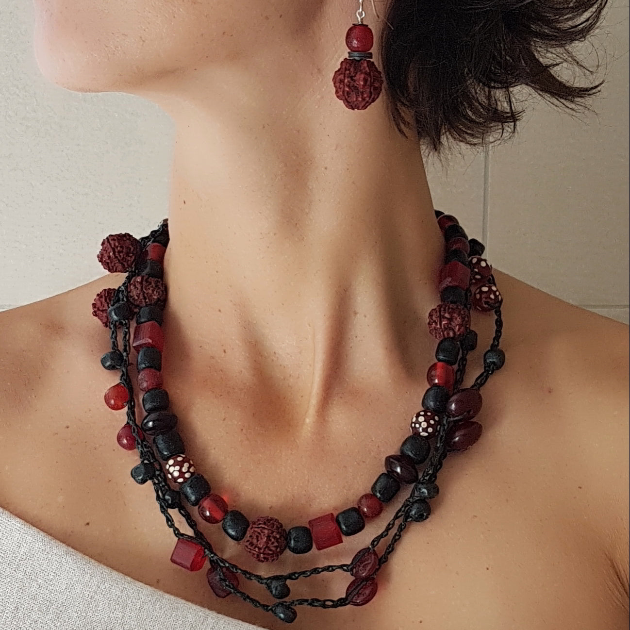 Lange handgehäkelte Kette mit Rudraksha-Samen aus nepalesischen Gebets-Malas, schwarzen indonesischen Wickelglasperlen, Harzperlen in Rottönen und roten Glasperlen von der Insel Java auf Baumwolle