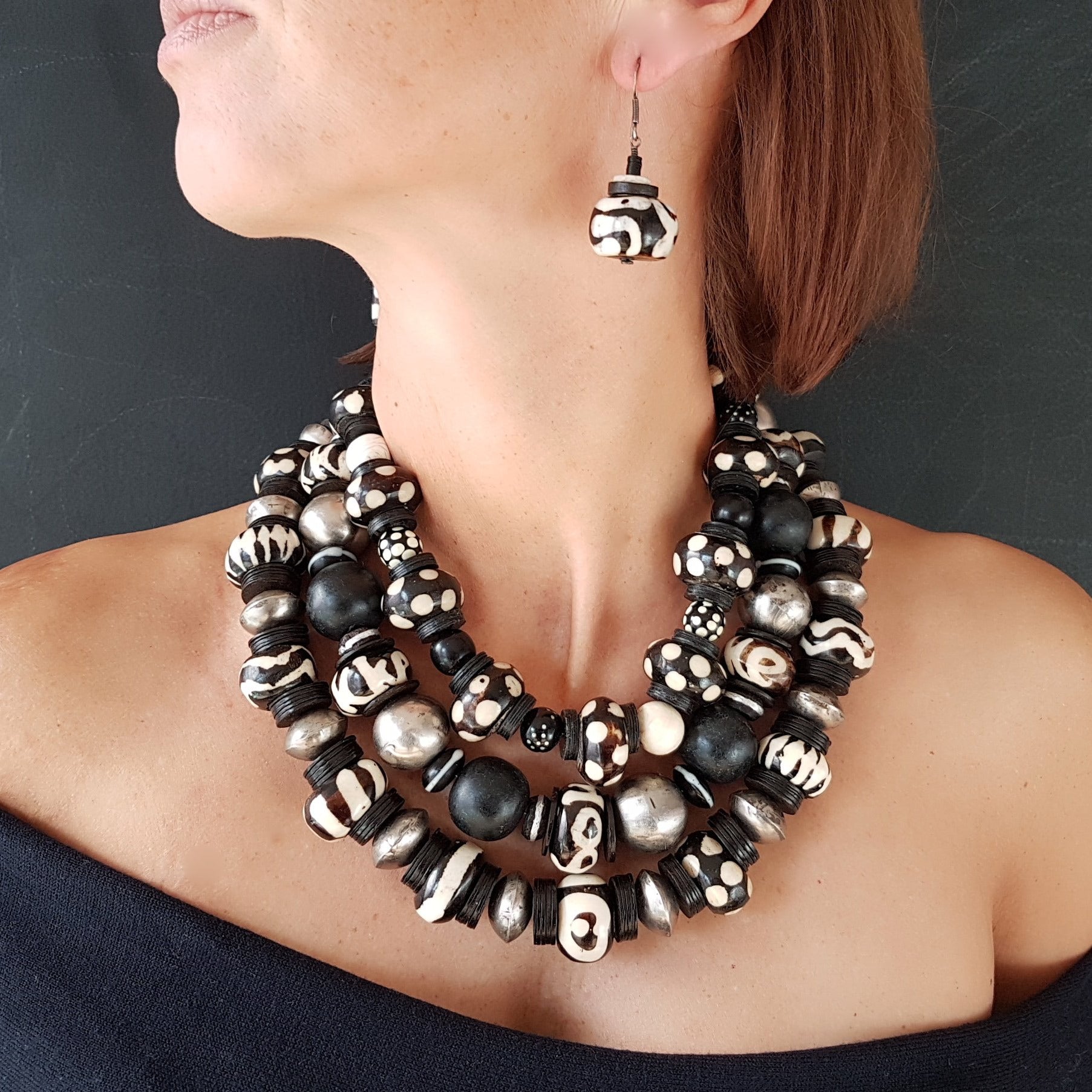 Handgearbeitete Kette mit gepunkteten gebatikten Beinperlen aus Afrika, schwarzen afrikanischen Bakelitscheiben und Perlen aus Glas, Muschel, Horn und Ebenholz mit Silberverschluss