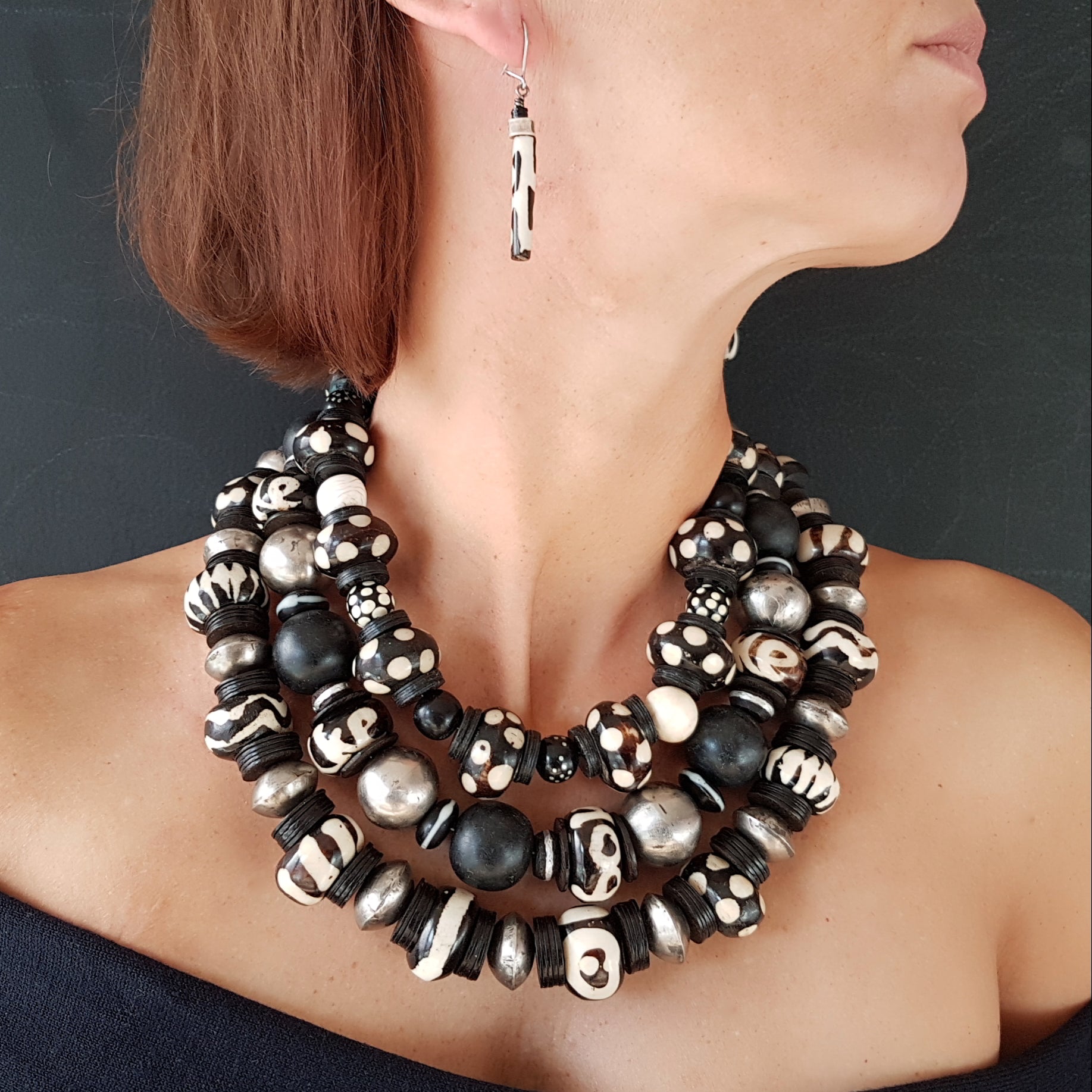 Handgearbeitete Kette mit gepunkteten gebatikten Beinperlen aus Afrika, schwarzen afrikanischen Bakelitscheiben und Perlen aus Glas, Muschel, Horn und Ebenholz mit Silberverschluss