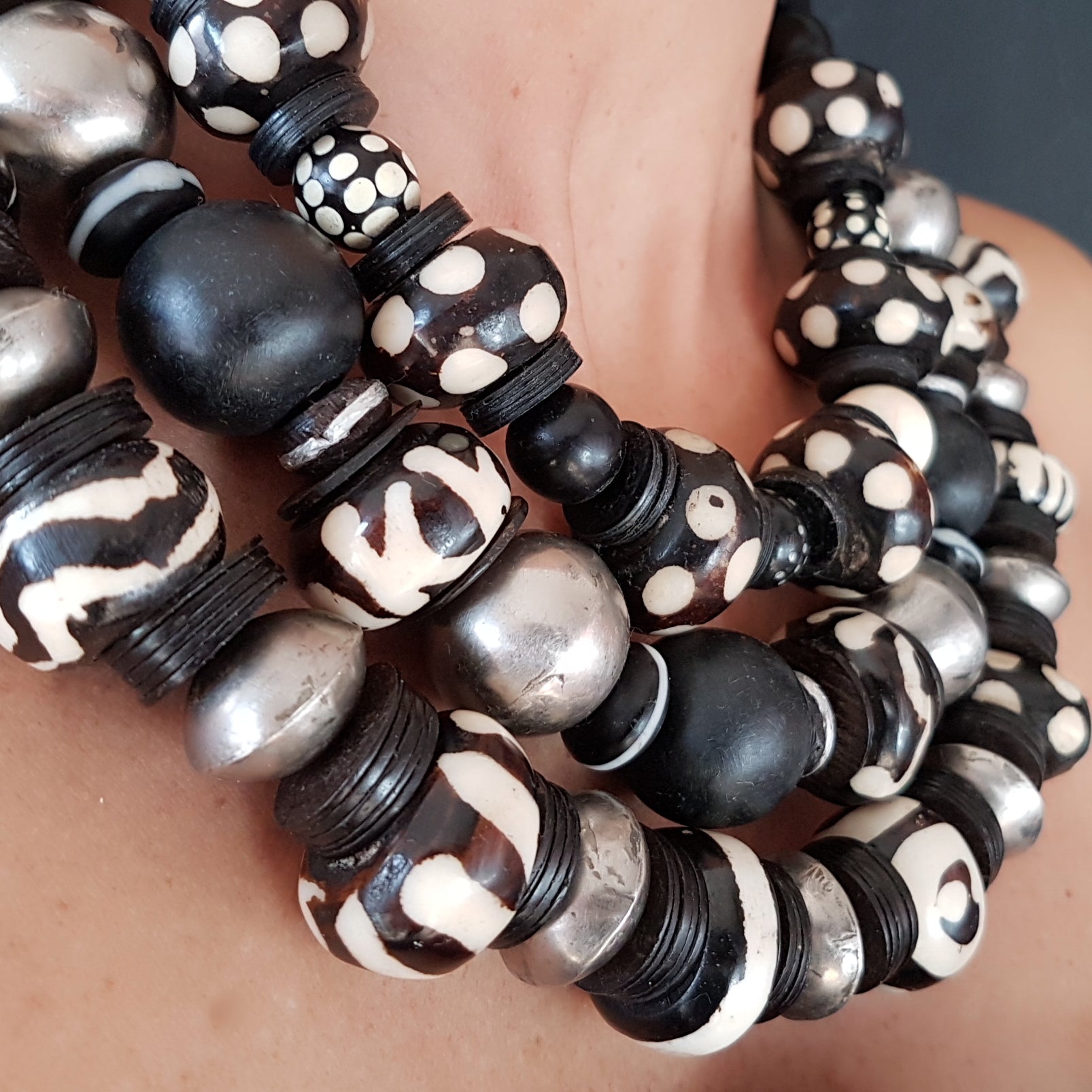 Handgearbeitete Kette mit gepunkteten gebatikten Beinperlen aus Afrika, schwarzen afrikanischen Bakelitscheiben und Perlen aus Glas, Muschel, Horn und Ebenholz mit Silberverschluss