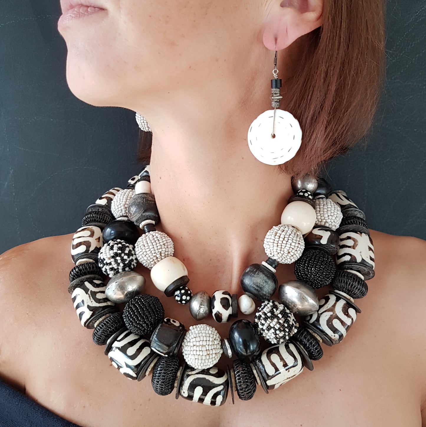 Handgearbeitete Kette mit schwarzweißen Glasperlen-Perlen, schwarzen Hornkugeln aus Indonesien, gebatikten Beinperlen aus Afrika, hohlen Metallperlen der Tuareg, dunklen afrikanischen Kokosscheiben und Ebenholz aus Nordafrika mit Silberverschluss