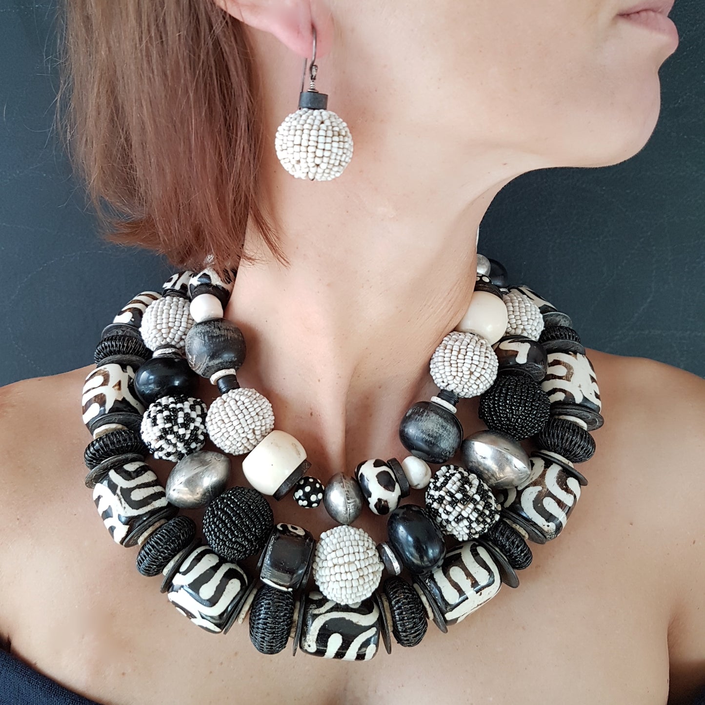 Handgearbeitete Kette mit schwarzweißen Glasperlen-Perlen, schwarzen Hornkugeln aus Indonesien, gebatikten Beinperlen aus Afrika, hohlen Metallperlen der Tuareg, dunklen afrikanischen Kokosscheiben und Ebenholz aus Nordafrika mit Silberverschluss