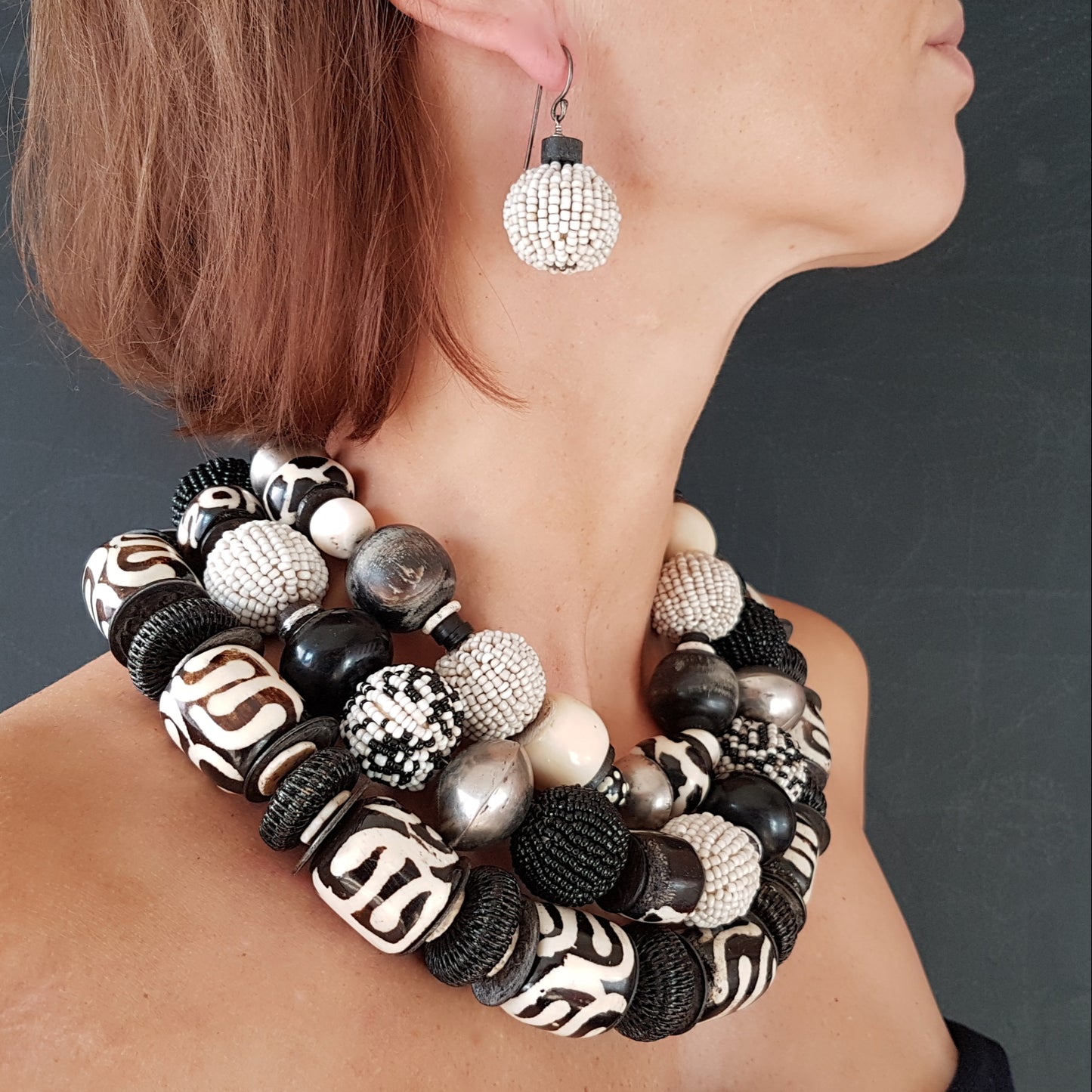 Handgearbeitete Kette mit schwarzweißen Glasperlen-Perlen, schwarzen Hornkugeln aus Indonesien, gebatikten Beinperlen aus Afrika, hohlen Metallperlen der Tuareg, dunklen afrikanischen Kokosscheiben und Ebenholz aus Nordafrika mit Silberverschluss