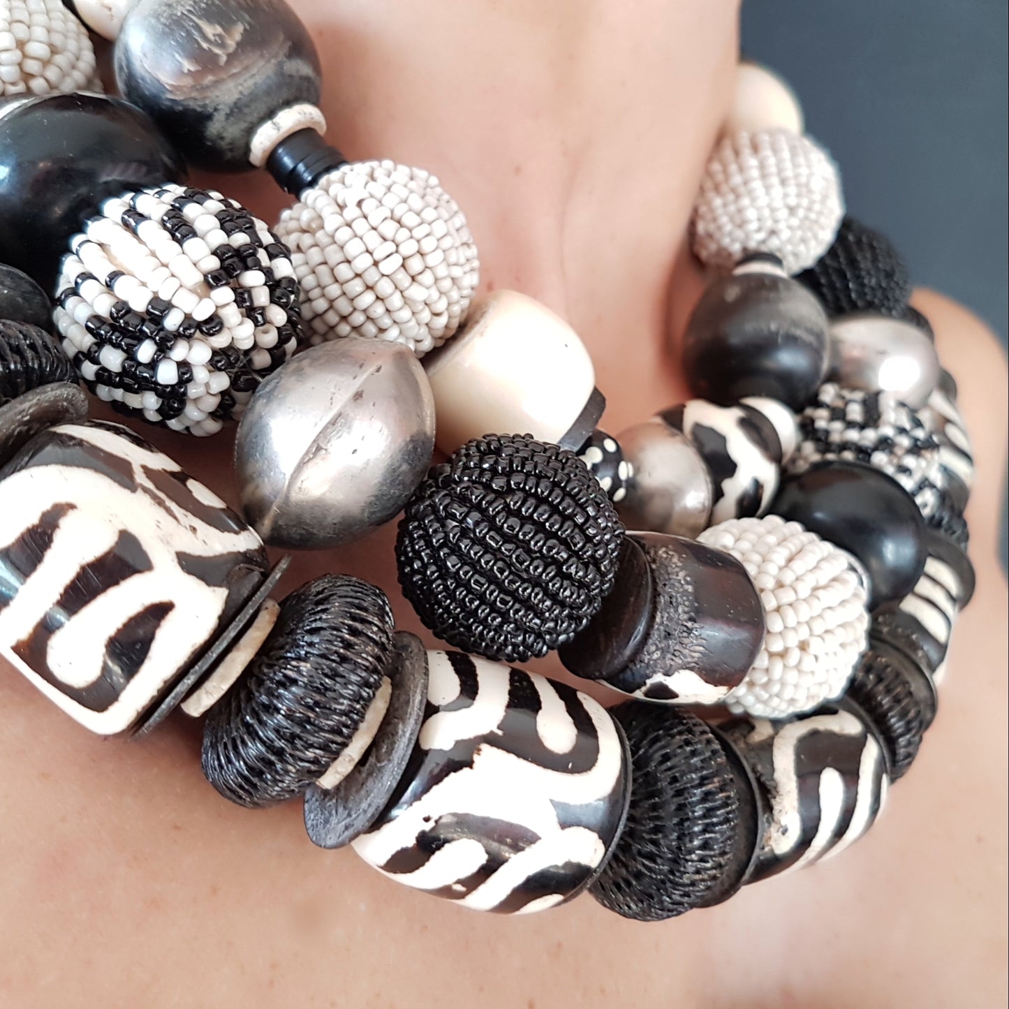 Handgearbeitete Kette mit schwarzweißen Glasperlen-Perlen, schwarzen Hornkugeln aus Indonesien, gebatikten Beinperlen aus Afrika, hohlen Metallperlen der Tuareg, dunklen afrikanischen Kokosscheiben und Ebenholz aus Nordafrika mit Silberverschluss