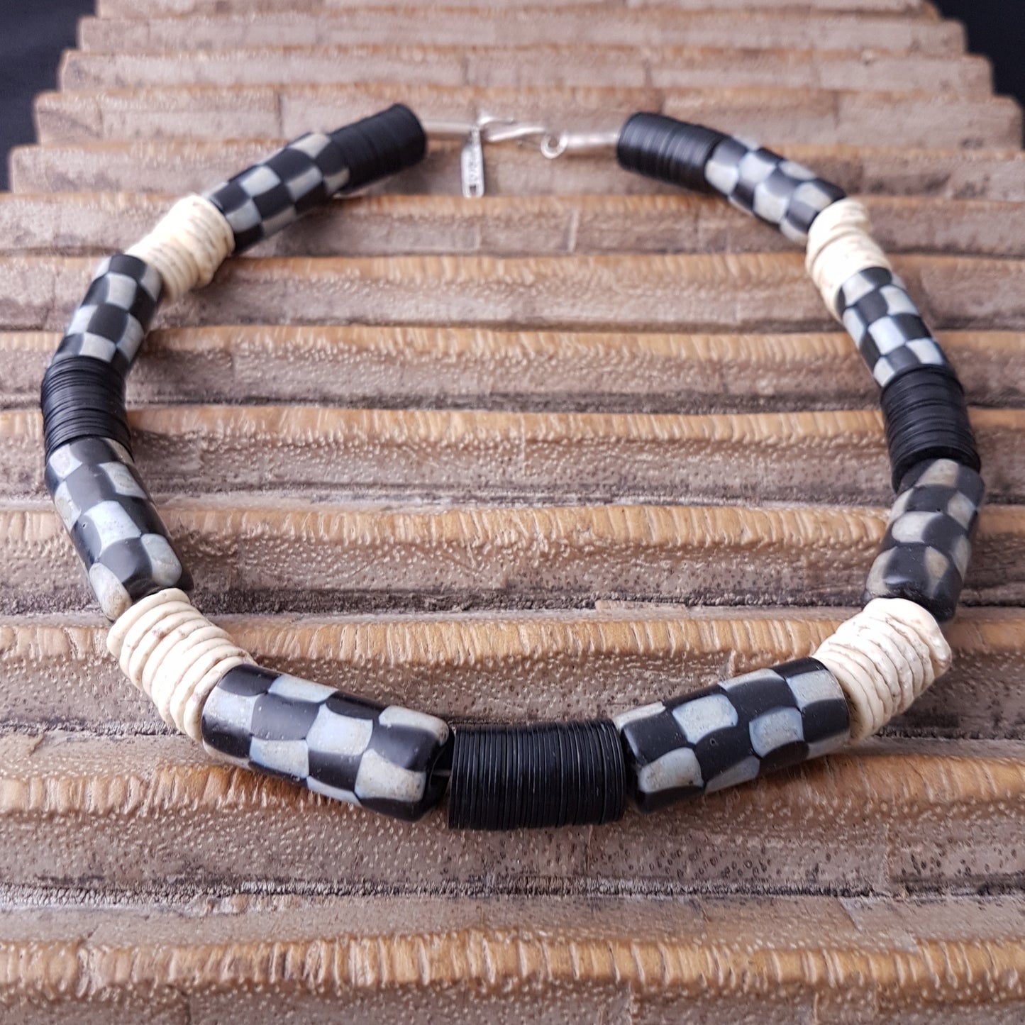 Handgearbeitete Kette mit schwarzweißen karrierten Glasperlen von der Insel Java, weißen Scheiben aus Straußeneierschale und schwarzen afrikanischen Bakelitscheiben mit Silberverschluss