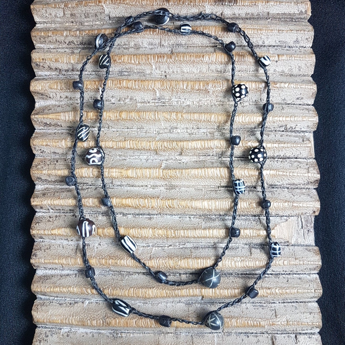 Lange handgehäkelte Kette mit schwarzen indonesischen Wickelglasperlen, gemusterten Harzperlen und vielfältigen schwarz-weißen Glasperlen von der Insel Java auf Baumwolle