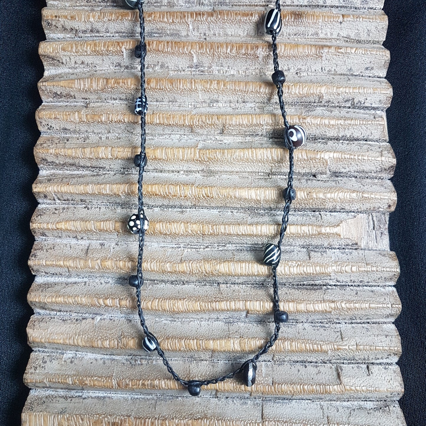 Lange handgehäkelte Kette mit schwarzen indonesischen Wickelglasperlen, gemusterten Harzperlen und vielfältigen schwarz-weißen Glasperlen von der Insel Java auf Baumwolle