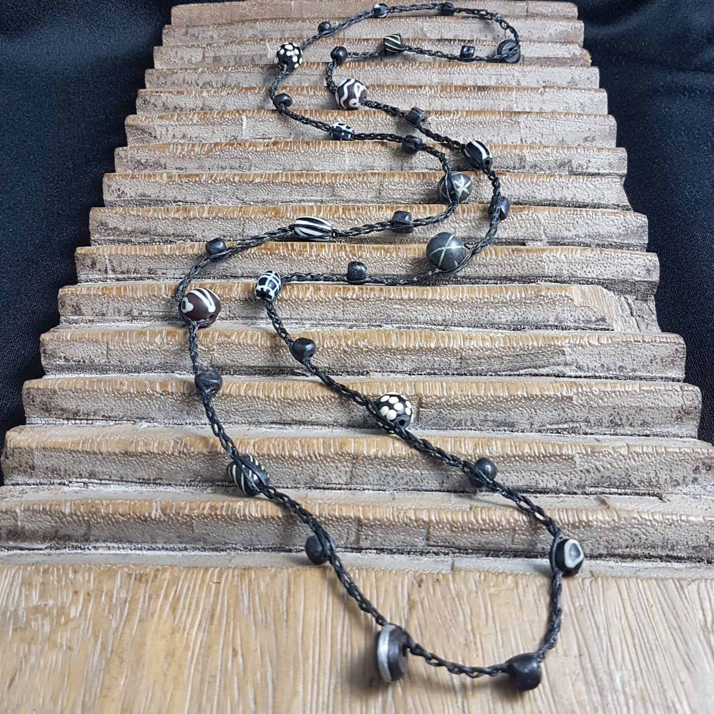 Lange handgehäkelte Kette mit schwarzen indonesischen Wickelglasperlen, gemusterten Harzperlen und vielfältigen schwarz-weißen Glasperlen von der Insel Java auf Baumwolle