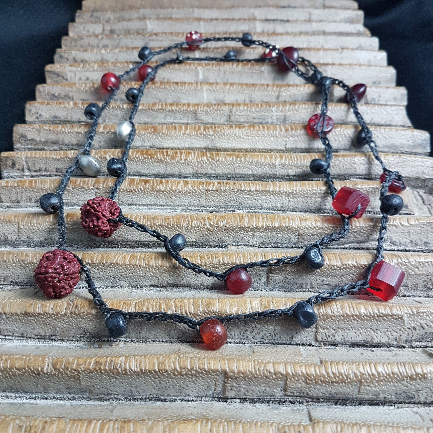 Lange handgehäkelte Kette mit Rudraksha-Samen aus nepalesischen Gebets-Malas, schwarzen indonesischen Wickelglasperlen, Harzperlen in Rottönen und roten Glasperlen von der Insel Java auf Baumwolle