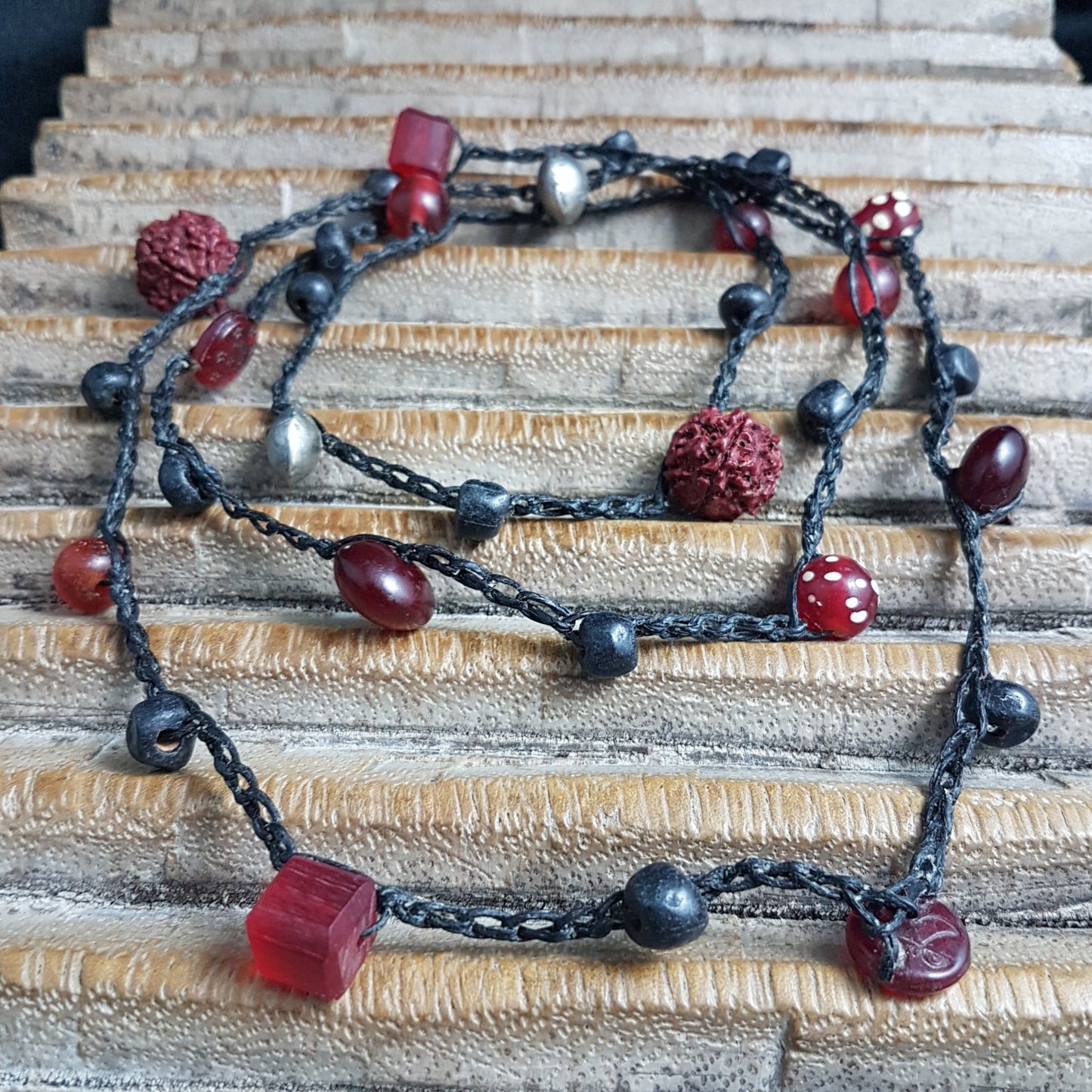 Lange handgehäkelte Kette mit Rudraksha-Samen aus nepalesischen Gebets-Malas, schwarzen indonesischen Wickelglasperlen, Harzperlen in Rottönen und roten Glasperlen von der Insel Java auf Baumwolle
