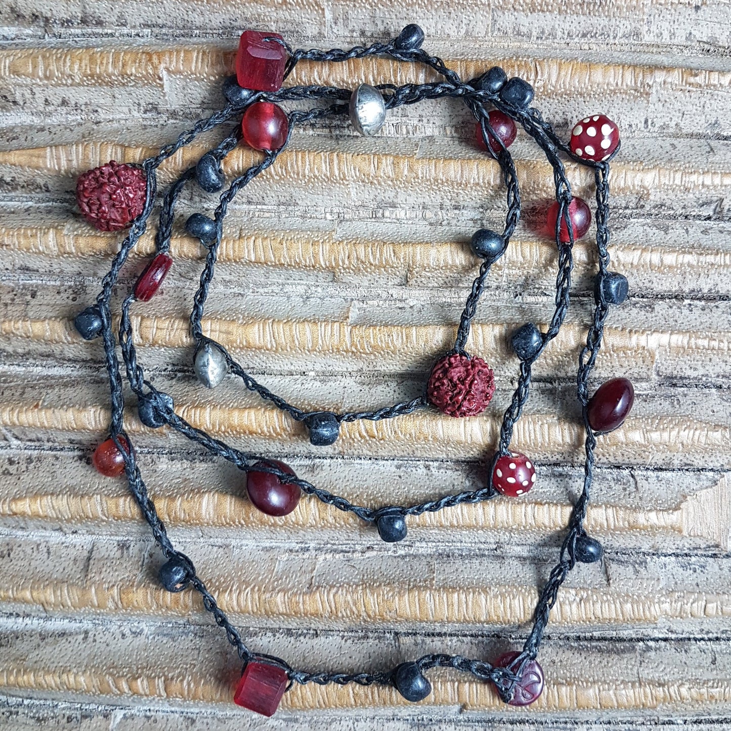 Lange handgehäkelte Kette mit Rudraksha-Samen aus nepalesischen Gebets-Malas, schwarzen indonesischen Wickelglasperlen, Harzperlen in Rottönen und roten Glasperlen von der Insel Java auf Baumwolle