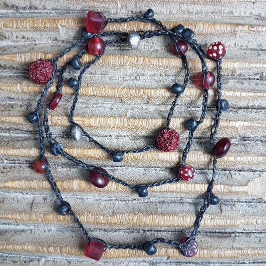 Lange handgehäkelte Kette mit Rudraksha-Samen aus nepalesischen Gebets-Malas, schwarzen indonesischen Wickelglasperlen, Harzperlen in Rottönen und roten Glasperlen von der Insel Java auf Baumwolle