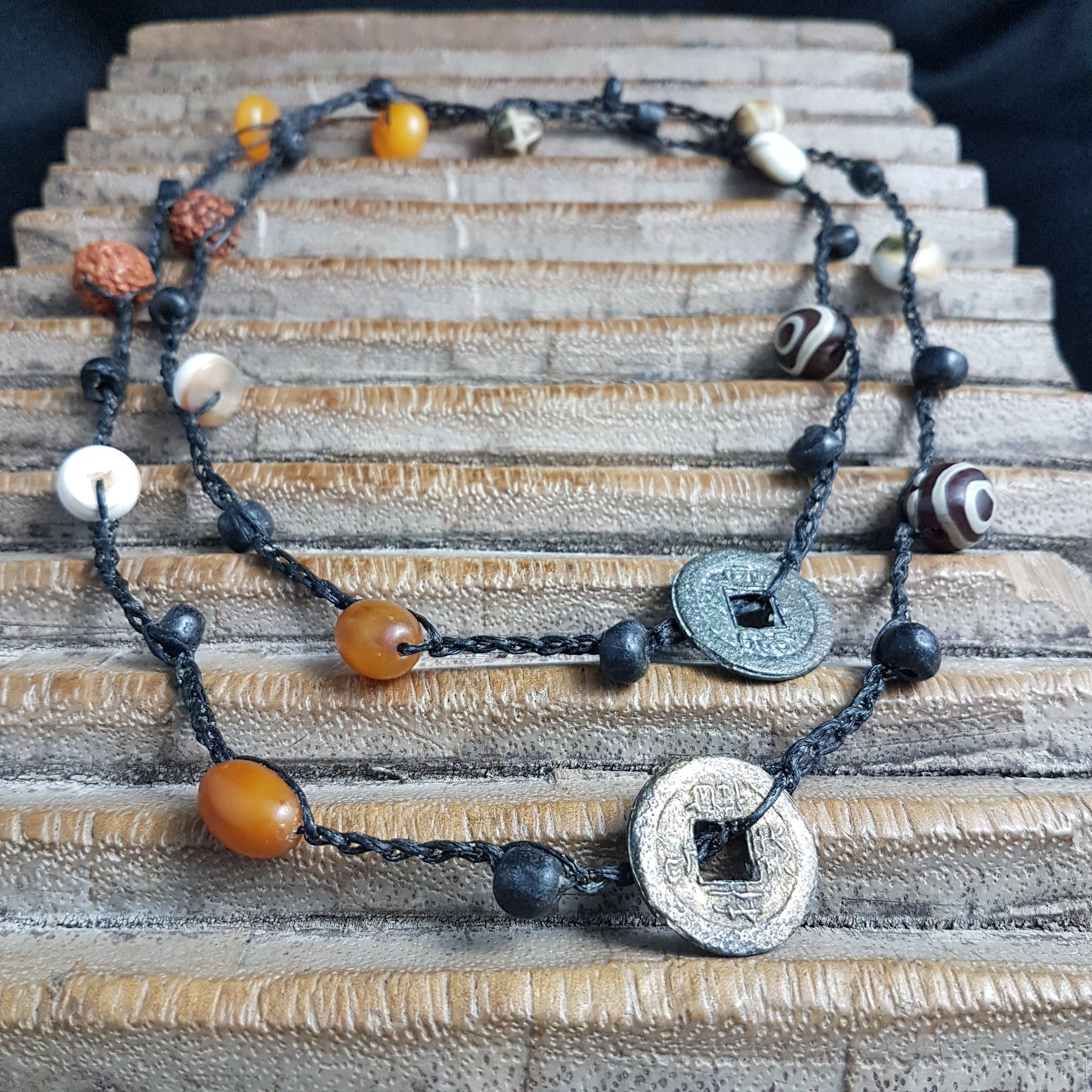 Lange handgehäkelte Kette mit Rudraksha-Samen aus nepalesischen Gebets-Malas, schwarzen indonesischen Wickelglasperlen, braunen und gelben Harzperlen, weißen Shiva-Muscheln und gestreiften Perlen aus versteinertem Holz aus Burma auf Baumwolle