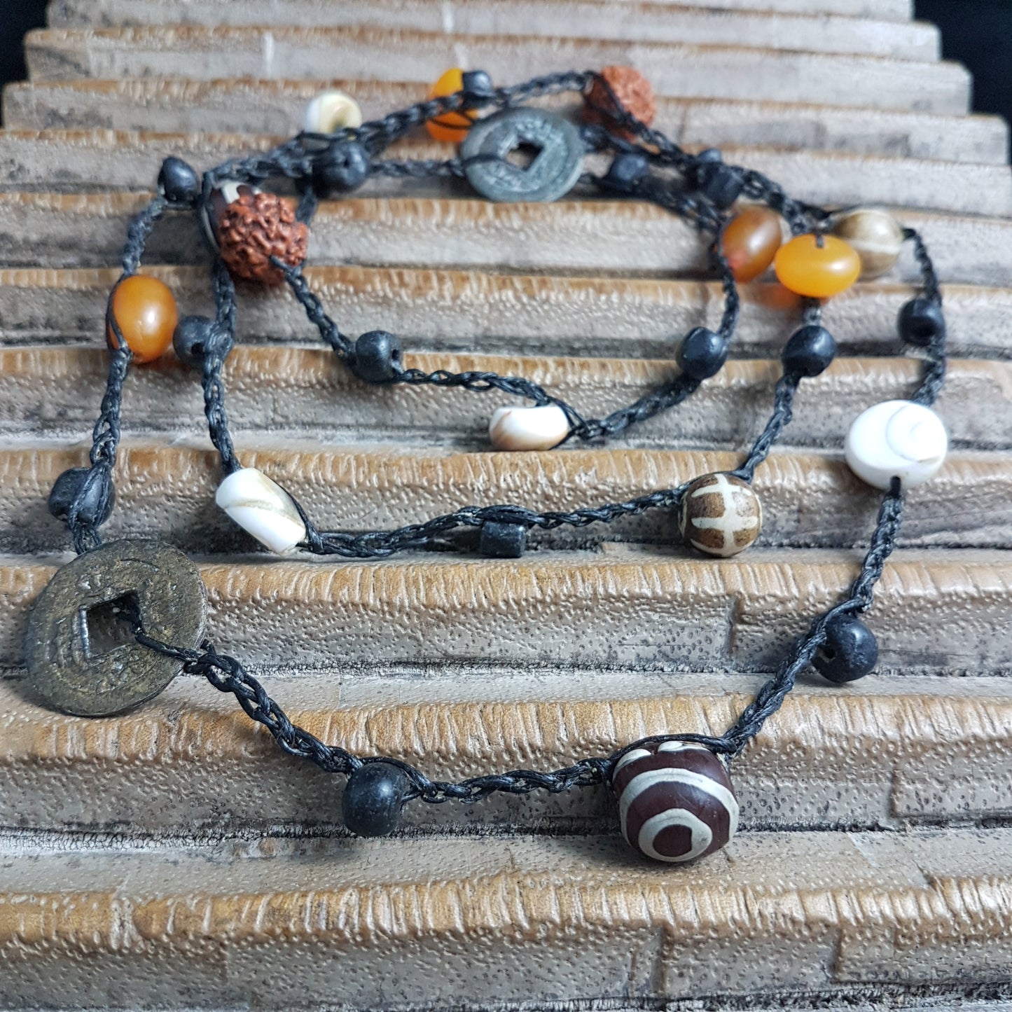 Lange handgehäkelte Kette mit Rudraksha-Samen aus nepalesischen Gebets-Malas, schwarzen indonesischen Wickelglasperlen, braunen und gelben Harzperlen, weißen Shiva-Muscheln und gestreiften Perlen aus versteinertem Holz aus Burma auf Baumwolle
