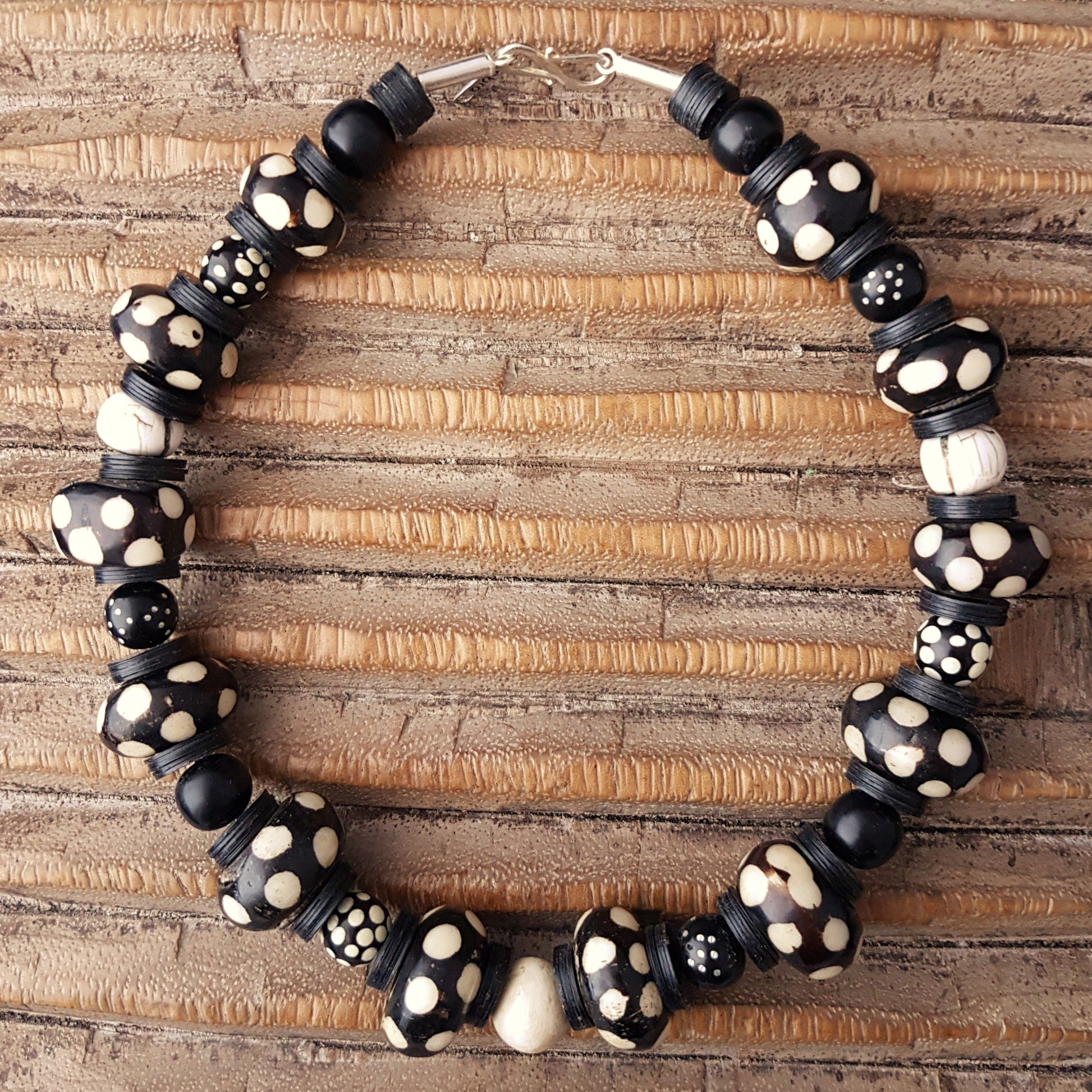 Handgearbeitete Kette mit gepunkteten gebatikten Beinperlen aus Afrika, schwarzen afrikanischen Bakelitscheiben und Perlen aus Glas, Muschel, Horn und Ebenholz mit Silberverschluss