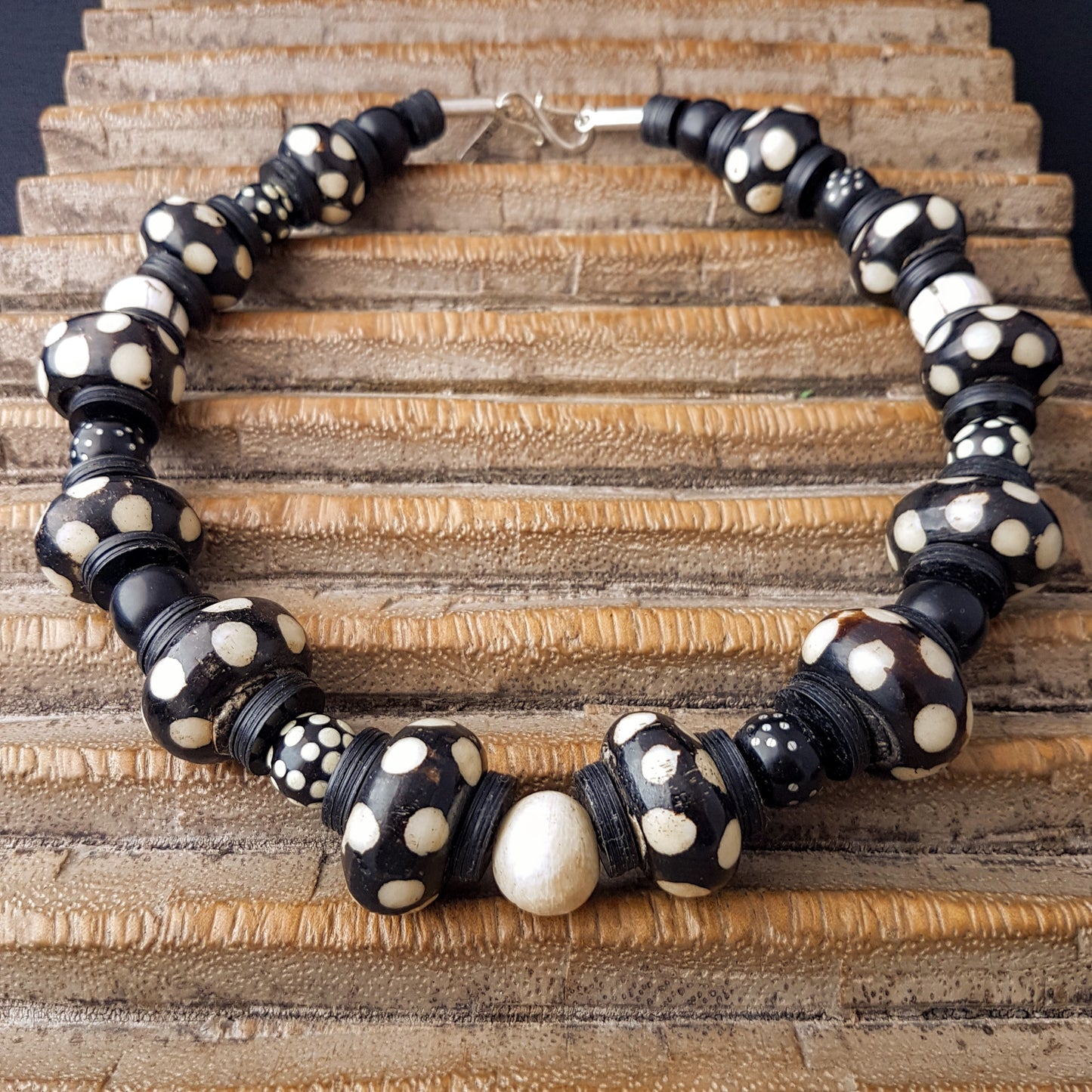 Handgearbeitete Kette mit gepunkteten gebatikten Beinperlen aus Afrika, schwarzen afrikanischen Bakelitscheiben und Perlen aus Glas, Muschel, Horn und Ebenholz mit SilberverschlussHandgearbeitete Kette mit gepunkteten gebatikten Beinperlen aus Afrika, schwarzen afrikanischen Bakelitscheiben und Perlen aus Glas, Muschel, Horn und Ebenholz mit Silberverschluss