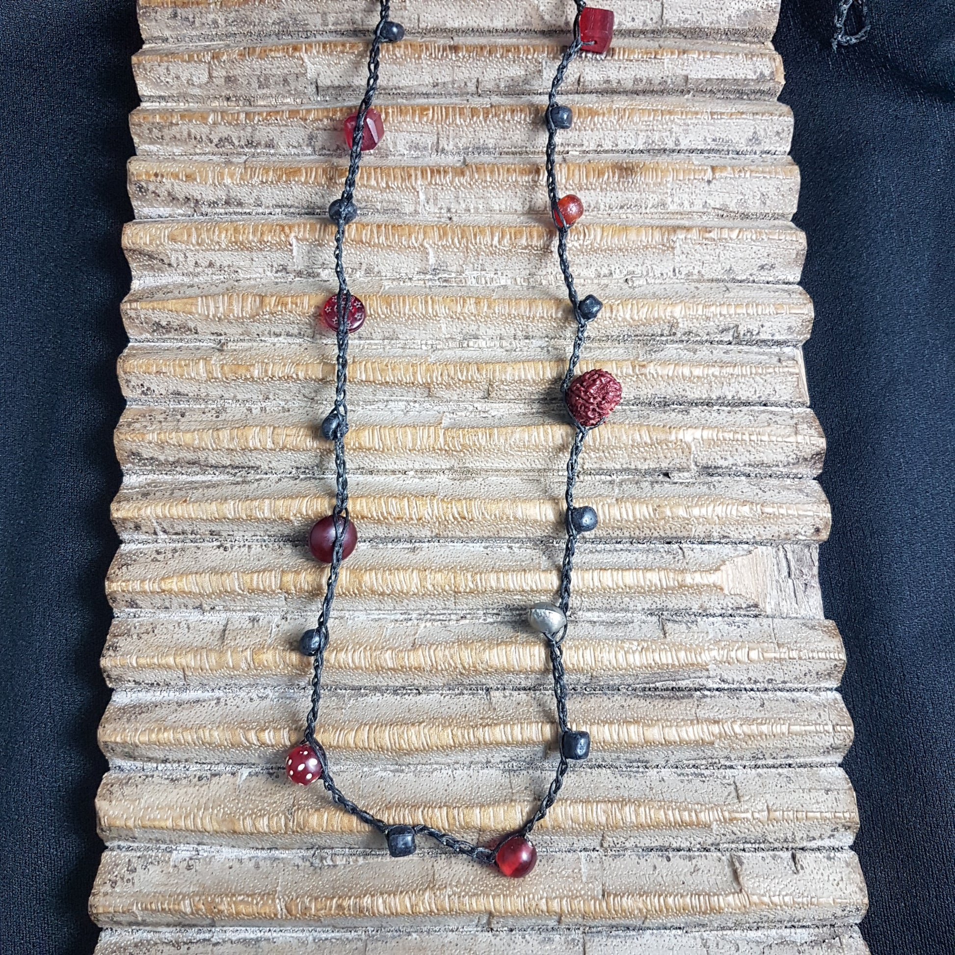 Lange handgehäkelte Kette mit Rudraksha-Samen aus nepalesischen Gebets-Malas, schwarzen indonesischen Wickelglasperlen, Harzperlen in Rottönen und roten Glasperlen von der Insel Java auf Baumwolle