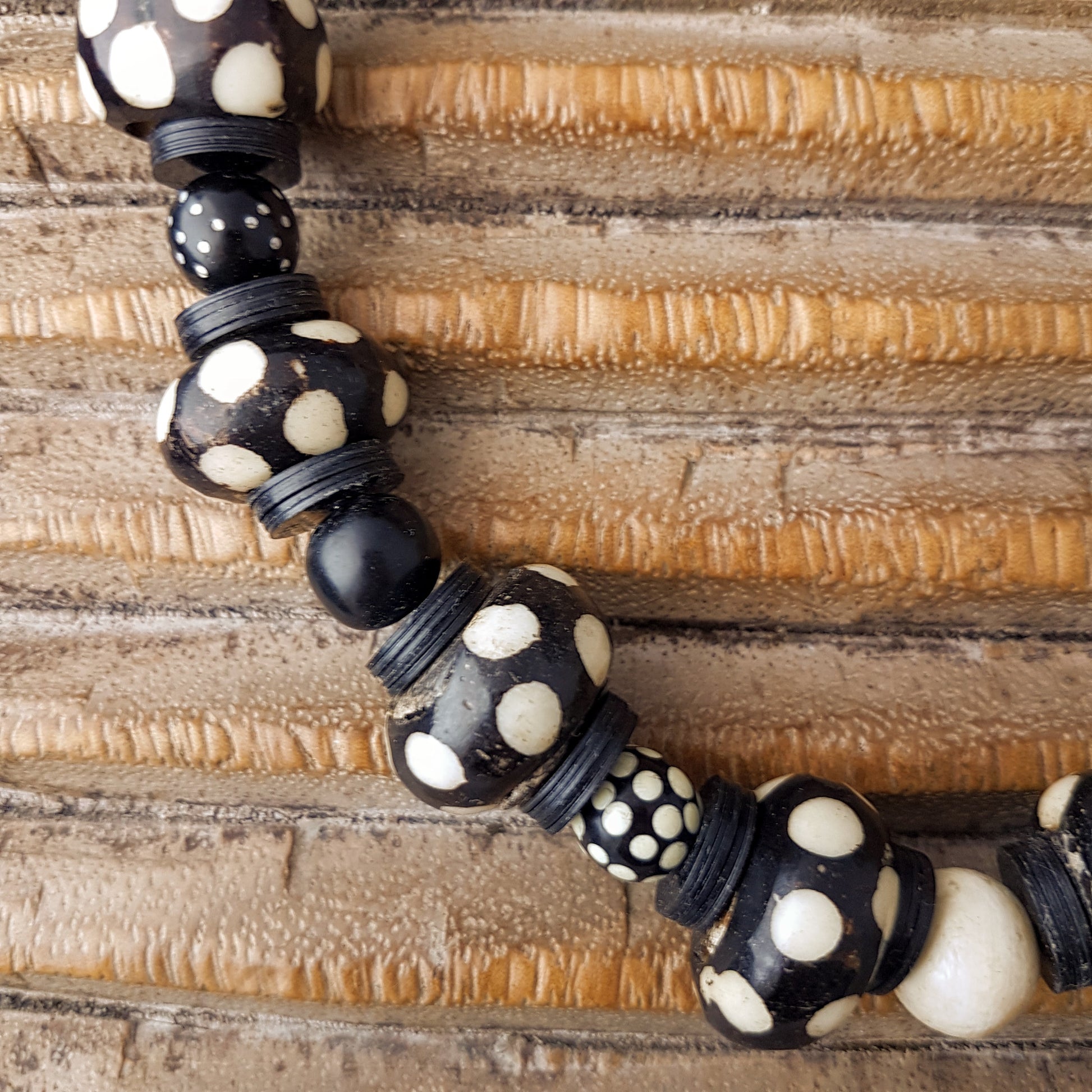 Handgearbeitete Kette mit gepunkteten gebatikten Beinperlen aus Afrika, schwarzen afrikanischen Bakelitscheiben und Perlen aus Glas, Muschel, Horn und Ebenholz mit Silberverschluss