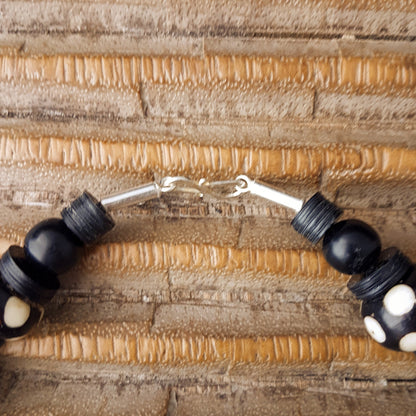 Handgearbeitete Kette mit gepunkteten gebatikten Beinperlen aus Afrika, schwarzen afrikanischen Bakelitscheiben und Perlen aus Glas, Muschel, Horn und Ebenholz mit Silberverschluss